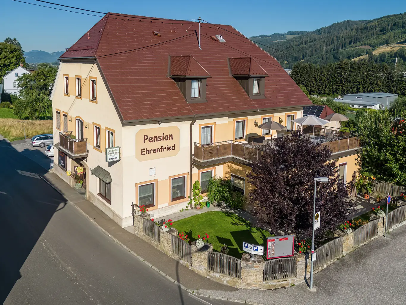 Außenansicht der familiengeführten Pension Ehrenfried, eingebettet in die grüne Hügellandschaft der Hochsteiermark