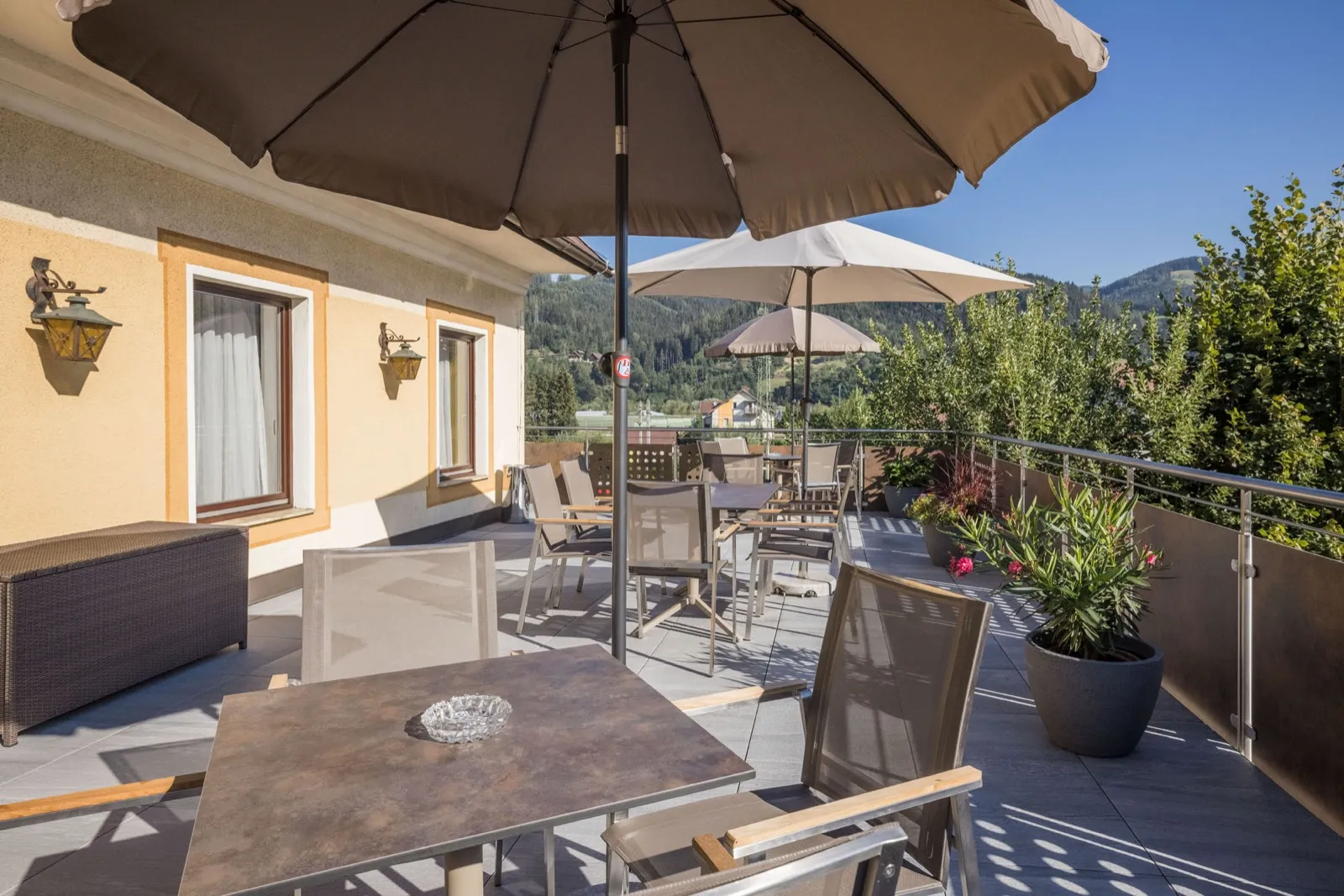 Sonnenterrasse mit Tischen und Sonnenschirm und Blick auf die umliegende Landschaft