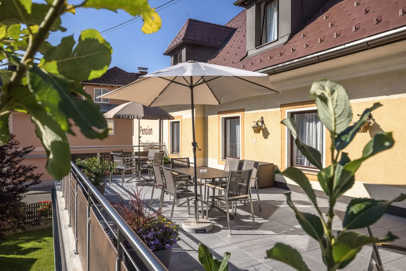 Terrasse der Pension Ehrenfried mit Sitzgruppen und Sonnenschirmen